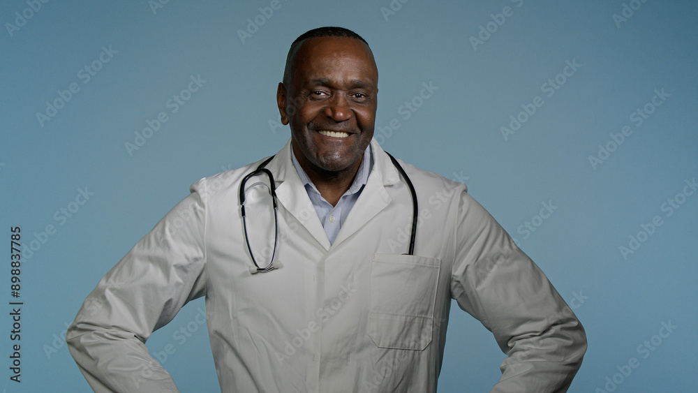 Smiling happy confident african american man professional physician male doctor successful ethnic medical worker clinic surgeon posing in studio blue background looking at camera healthcare medicine Smiling happy confident african american man professional physician male doctor successful ethnic medical worker clinic surgeon posing in studio blue background looking at camera healthcare medicine