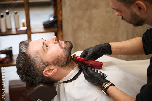 Εκτύπωση καμβά Focused barber trimming handsome man neck and beard, modeling the neckline
