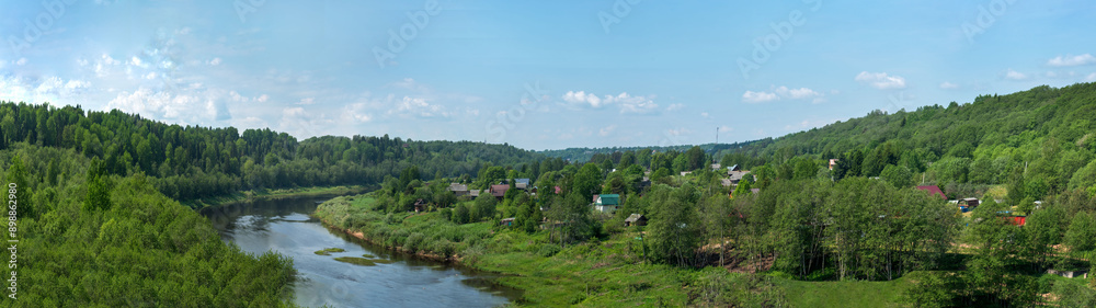 Obraz premium Panoramic view of the serene river surrounded by lush vegetation, on the shore of the village