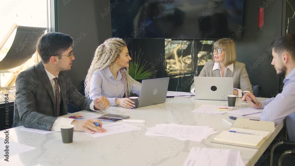 An elderly businesswoman manager talks with a group of the executive team, discussing the project plan and financial results in a modern office, using a laptop, charts, and various office supplies An elderly businesswoman manager talks with a group of the executive team, discussing the project plan and financial results in a modern office, using a laptop, charts, and various office supplies