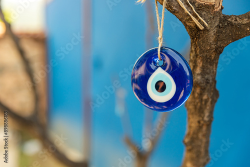 Foto evil eye bead hanging on the tree, space for text with blue background