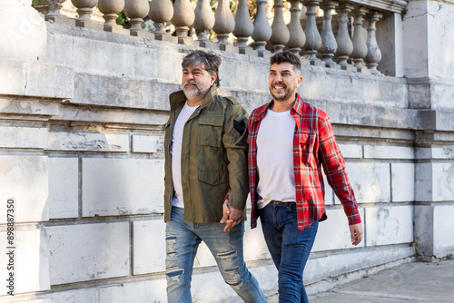 Two affectionate gay men walking on the street while holding hands photo