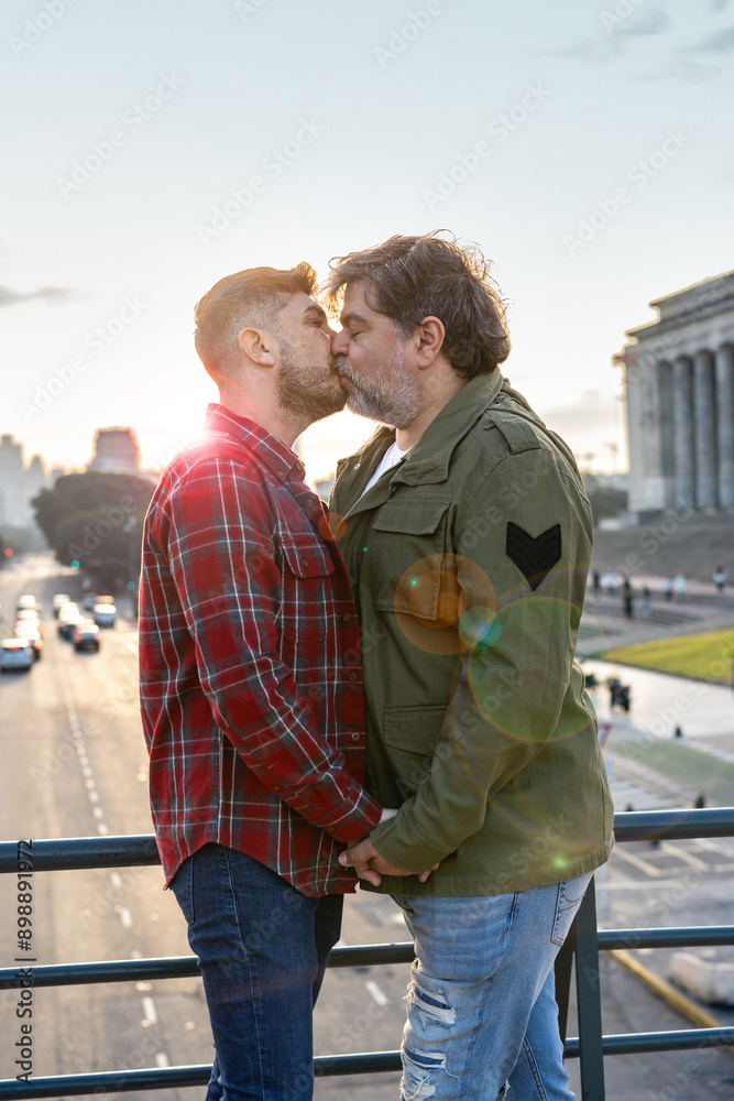 Hispanic gay couple kissing each other at sunset in Buenos Aires city. Vertical shot