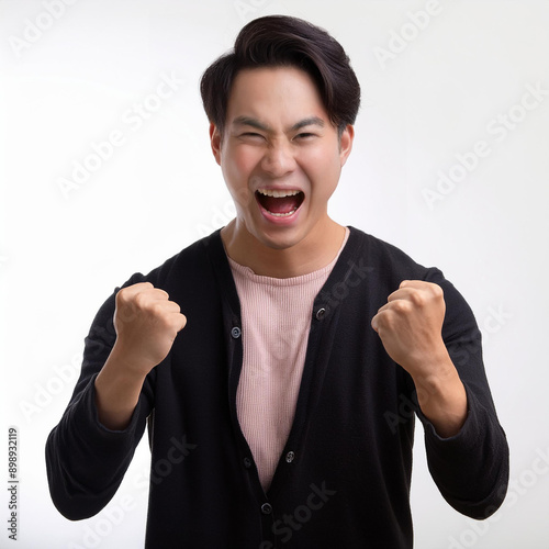 白い背景の前でガッツポーズをする若い男性。彼は黒いカーディガンとピンクのシャツを着用し、口を大きく開けて喜びを表現しています。短い髪は整えられ、エネルギッシュで自信に満ちた表情をしています。generative AI