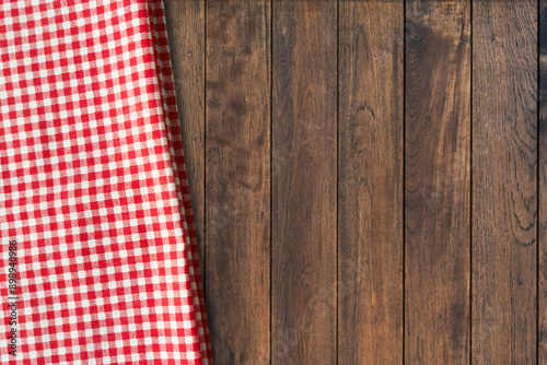 Top view of red gingham checkered table cloth on old wooden table background. Picnic napkin kitchen backdrop.
