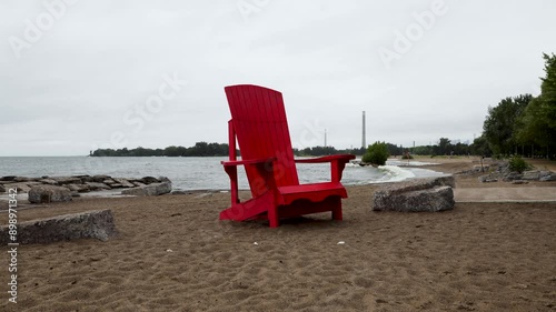 Big Red Muskoka chair standing on the Beach in a rain storm