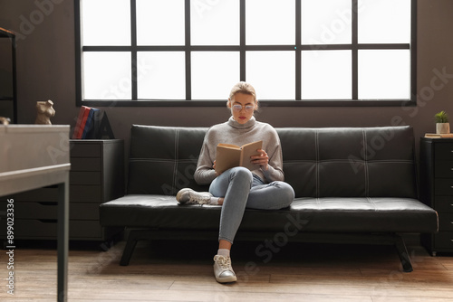 Young woman reading book on couch at home