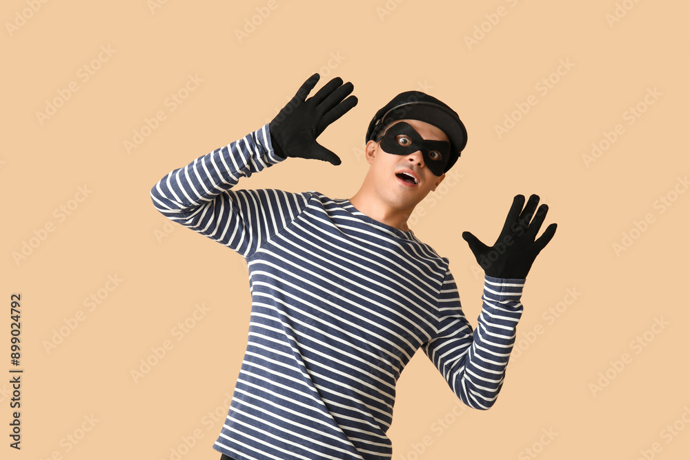 Male thief with raised hands on beige background Male thief with raised hands on beige background