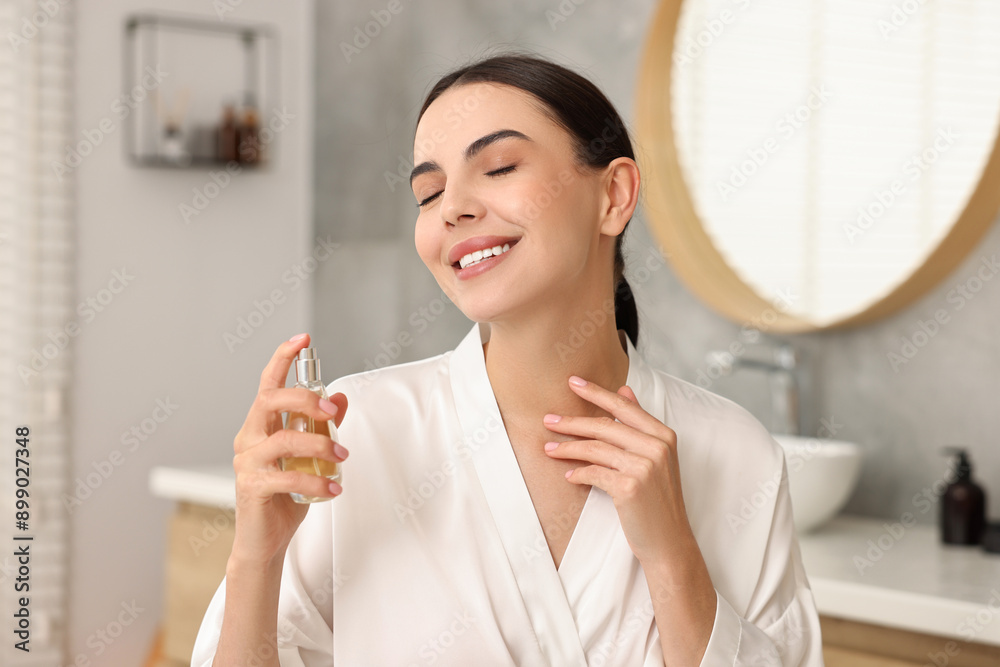 Smiling woman spraying aromatic perfume in bathroom Smiling woman spraying aromatic perfume in bathroom