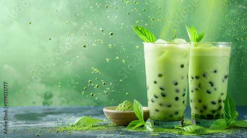 Two plastic transparent glasses with delicious matcha green milk tea and tapioca balls for advertisement background, copy space, banner template, splashing refreshing summer vibe
