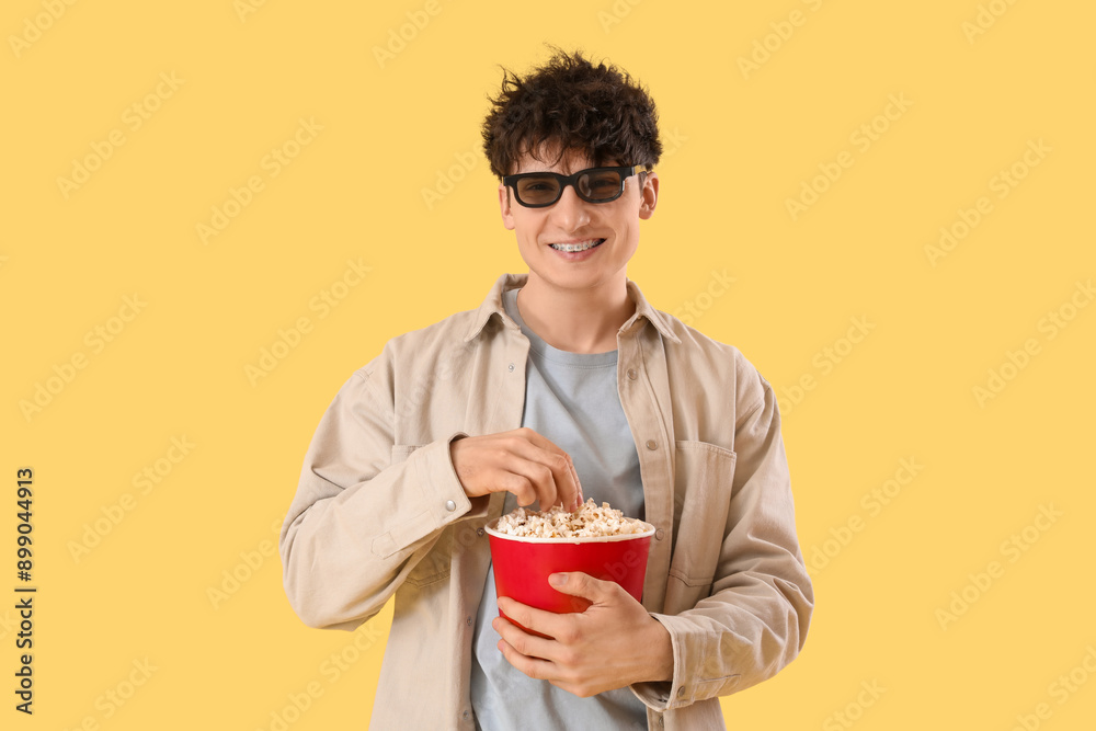 Young man in 3d eyeglasses eating popcorn on yellow background Young man in 3d eyeglasses eating popcorn on yellow background