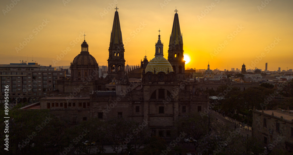 A breathtaking aerial panoramic view of Guadalajara, Mexico, during a spectacular sunset. The majestic sun sets on the horizon, with the city's iconic cathedral and its distinctive yellow domes promin A breathtaking aerial panoramic view of Guadalajara, Mexico, during a spectacular sunset. The majestic sun sets on the horizon, with the city's iconic cathedral and its distinctive yellow domes promin