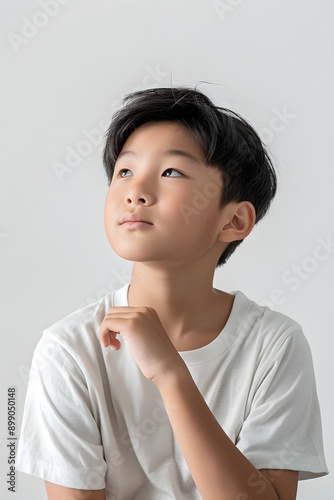 Little child thinking with hand on chin wearing t-shirt in studio on white background