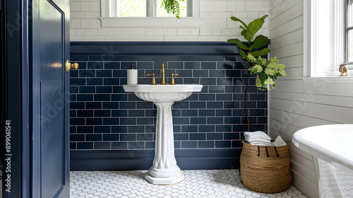 Elegant bathroom in coastal villa. Features white hexagon tile floor, navy blue subway tile walls, single pedestal sink, and brass fixtures