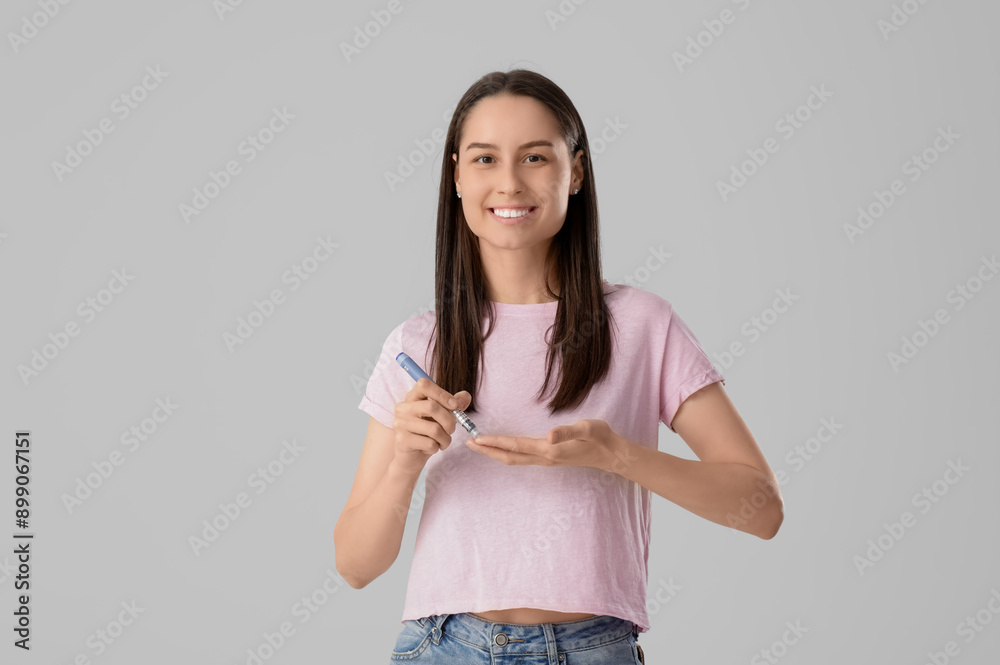 Diabetic young woman using lancet pen on light background Diabetic young woman using lancet pen on light background