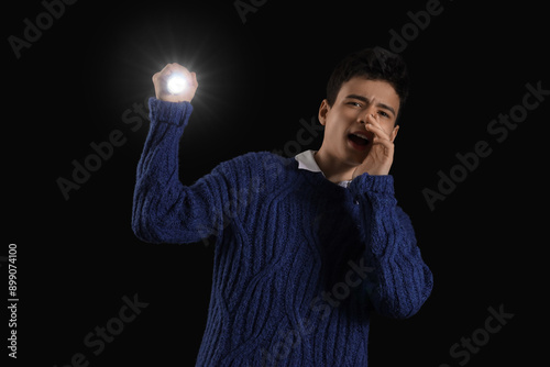 Teenage boy shining flashli...