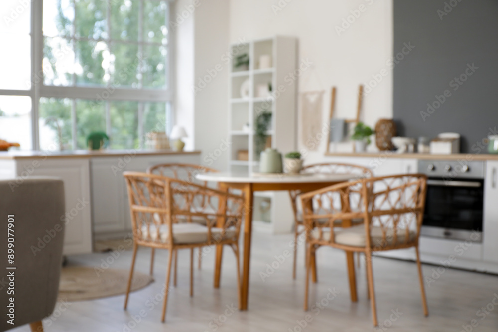 Blurred view of light kitchen with counters and dining table Blurred view of light kitchen with counters and dining table