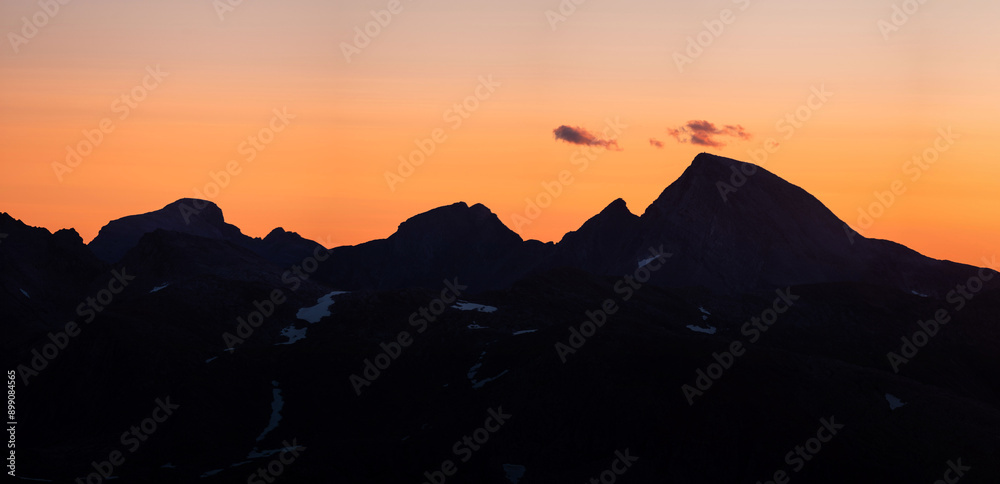Panorama of silhouettes of mountains seen from Tortenviktind. Summer midnight sun view over Svartisen nationalpark and saltfjellet. Fjelltur natt i Norge. Twilight and golden hour with blue mountains Panorama of silhouettes of mountains seen from Tortenviktind. Summer midnight sun view over Svartisen nationalpark and saltfjellet. Fjelltur natt i Norge. Twilight and golden hour with blue mountains
