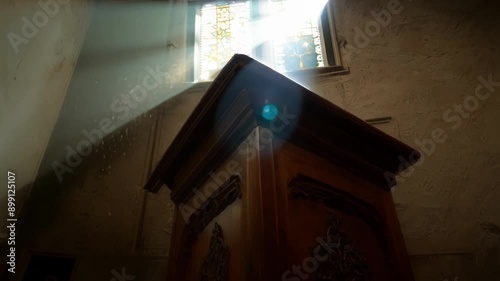 The wooden pulpit stands tall in the center of the dimly lit room highlighted by a single beam of light.