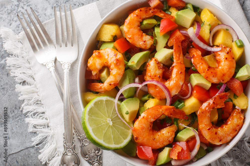Bright rich salad mango shrimp avocado with red onion, bell pepper close-up in a bowl on the table. Horizontal top view from above Bright rich salad mango shrimp avocado with red onion, bell pepper close-up in a bowl on the table. Horizontal top view from above