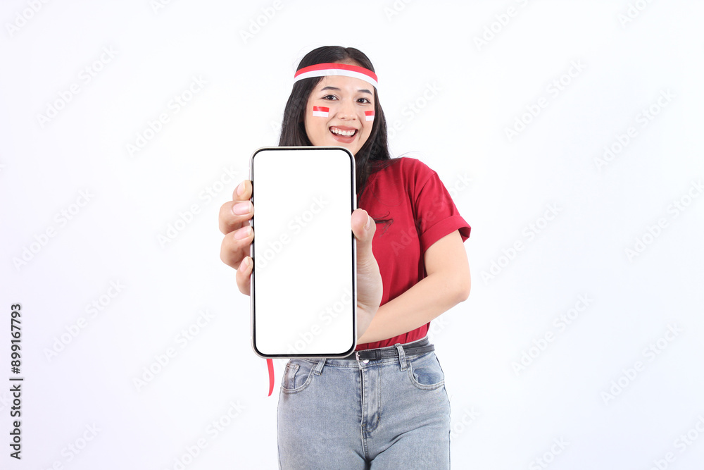 Excited young Asian woman with red white flag ribbon showing a screen mobile phone, for advertisement and presenting celebrating victory Indonesian independence day 17 Agustus. Merdeka concept Excited young Asian woman with red white flag ribbon showing a screen mobile phone, for advertisement and presenting celebrating victory Indonesian independence day 17 Agustus. Merdeka concept