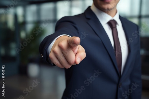 A professional in a business suit extends an authoritative finger, gesturing forward in a corporate environment. photo