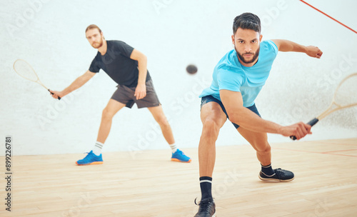 Men, playing and court or squash match, rubber ball and racket for sport with energy or fitness in challenge. Athlete, friends and competing in active hobby, wooden floor and training for competition © peopleimages.com