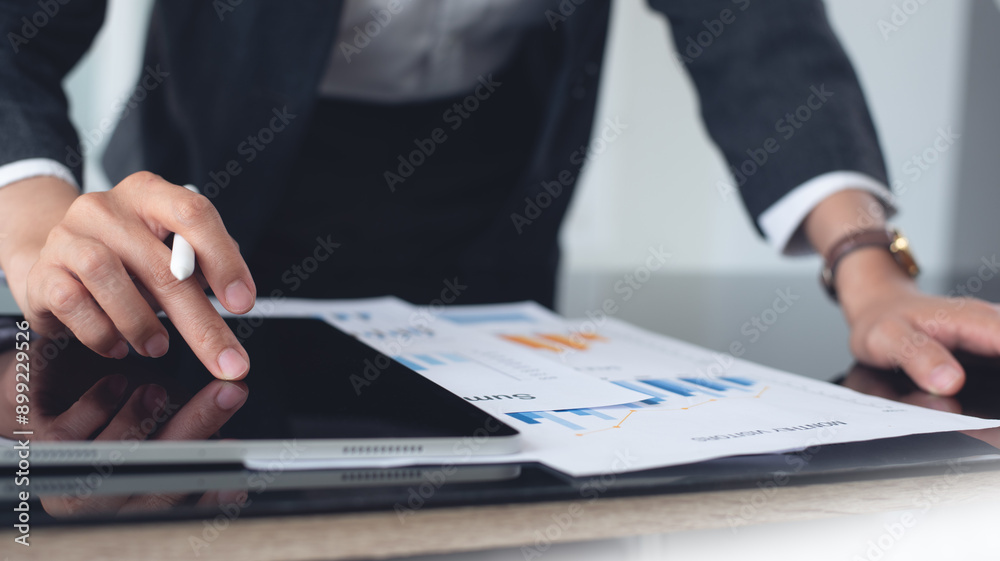 Business analyst using digital tablet analyzing financial statement, business report for audit internal control system. Businesswoman working with business documents at office Business analyst using digital tablet analyzing financial statement, business report for audit internal control system. Businesswoman working with business documents at office