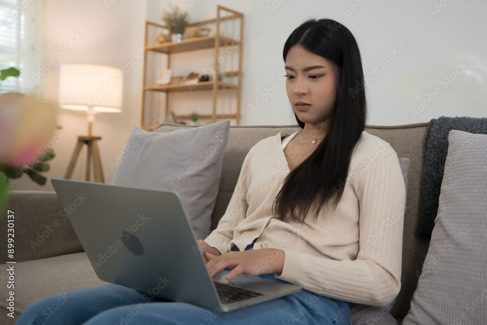 Young asian women putting laptop on legs and typing business report about marketing data of new startup while sitting on the couch to spending time and relaxation with enjoying lifestyle at home Young asian women putting laptop on legs and typing business report about marketing data of new startup while sitting on the couch to spending time and relaxation with enjoying lifestyle at home