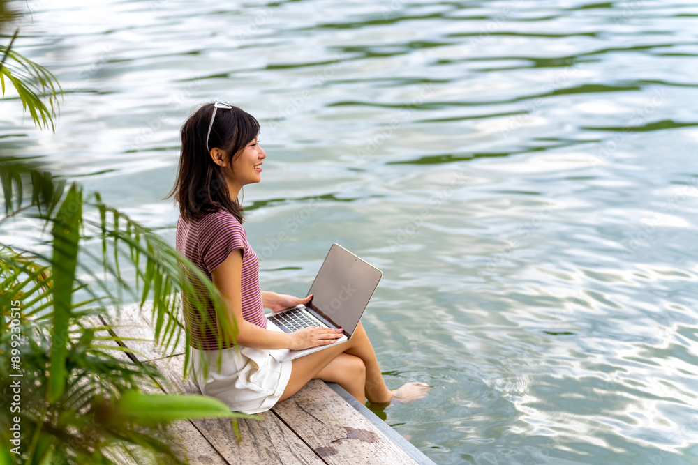 Happy Asian woman using laptop computer remote working online business on on lake house balcony. Attractive girl relax and enjoy outdoor lifestyle travel forest nature on summer holiday vacation. Happy Asian woman using laptop computer remote working online business on on lake house balcony. Attractive girl relax and enjoy outdoor lifestyle travel forest nature on summer holiday vacation.
