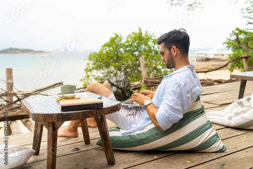 Caucasian businessman remote working online corporate business financial on laptop computer at beach cafe. People enjoy outdoor lifestyle travel tropical island on summer beach holiday vacation.