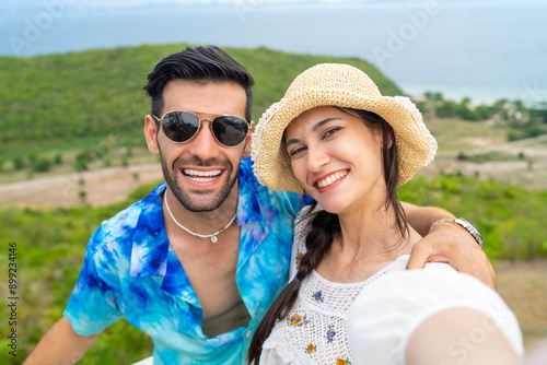 Happy Caucasian family couple using mobile phone taking selfie together at mountain peak on tropical island. Man and woman enjoy outdoor lifestyle travel nature ocean on summer beach holiday vacation. © CandyRetriever 