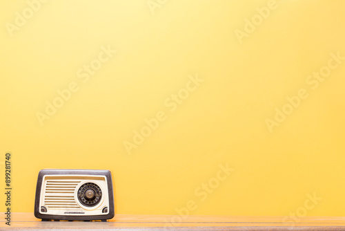 Retro old radio on the wooden shelf front gradient yellow background. Vintage style filtered photo