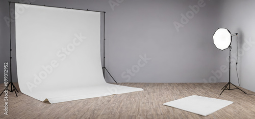 Professional photography studio setup, empty white backdrop, lighting equipment on stands, softbox, wooden floor for model shoots, product advertising photo