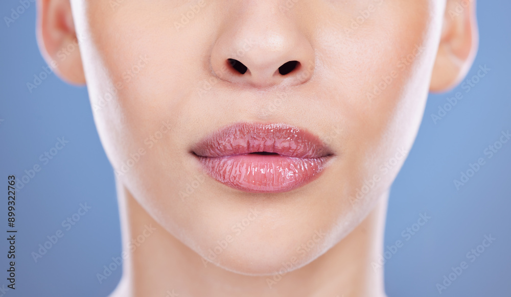 Obraz premium Face, woman and pouting lips for cosmetic, beauty or filler with closeup in blue background. Female person, mouth and zoom for wellness, sexy and seductive in studio backdrop for skincare or health