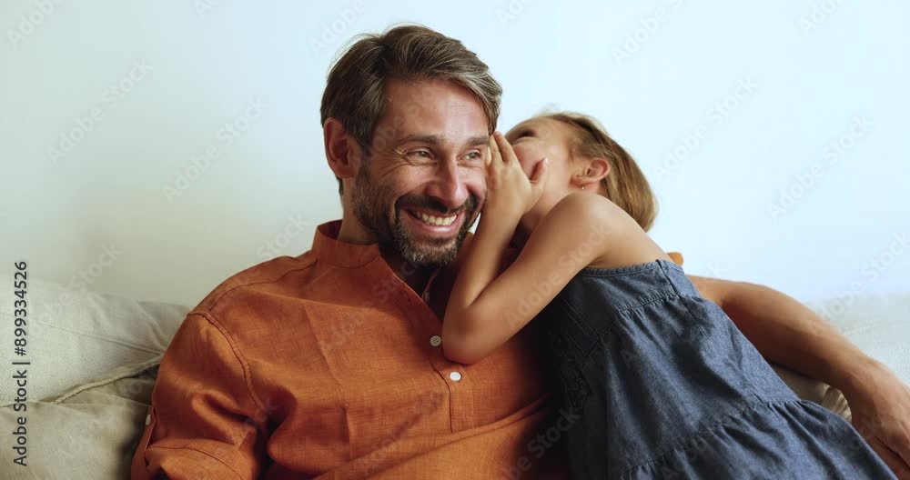 Cute little daughter kid whispering secret at dads ear. Happy daddy cuddling and listening to adorable girl, having fun at home, laughing, enjoying family leisure, closeness, fatherhood Cute little daughter kid whispering secret at dads ear. Happy daddy cuddling and listening to adorable girl, having fun at home, laughing, enjoying family leisure, closeness, fatherhood