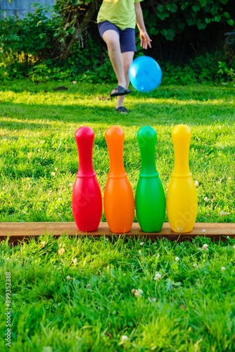 фотографія A boy in blue shorts and a yellow T -shirt plays a children's bowling in the yard