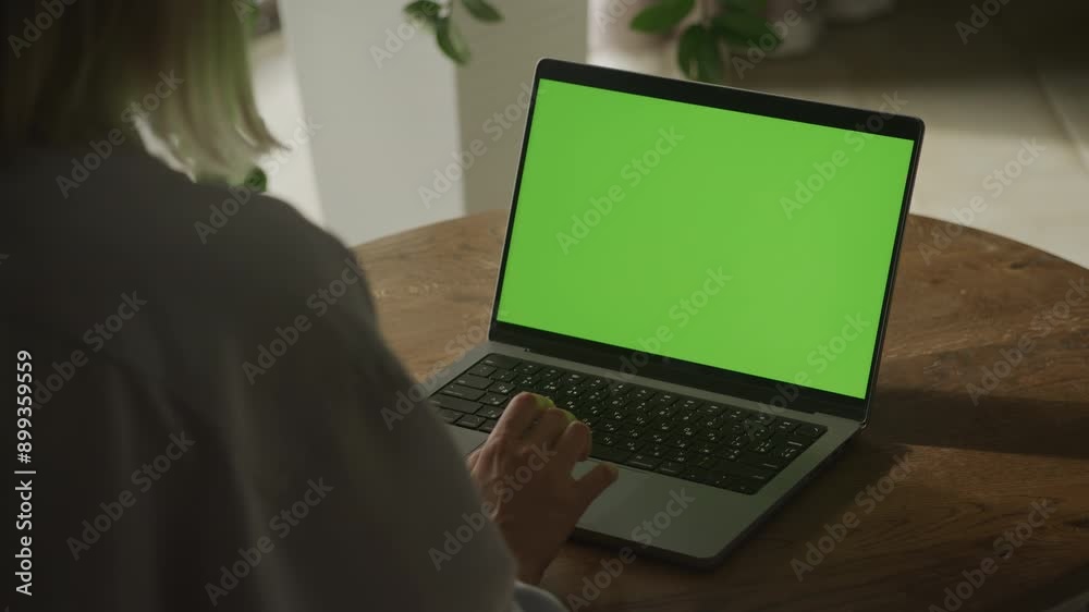 Person Using Laptop with Green Screen on Wooden Table Person Using Laptop with Green Screen on Wooden Table