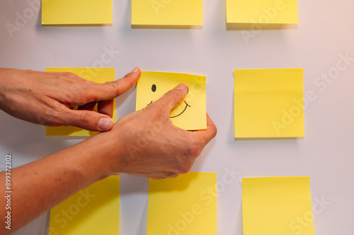 A person is holding a yellow sticky note with a smiley face on it. Concept of happiness and positivity photo