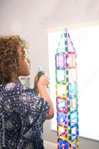 Young girl building a tall, colorful block, magnetic tile tower photo