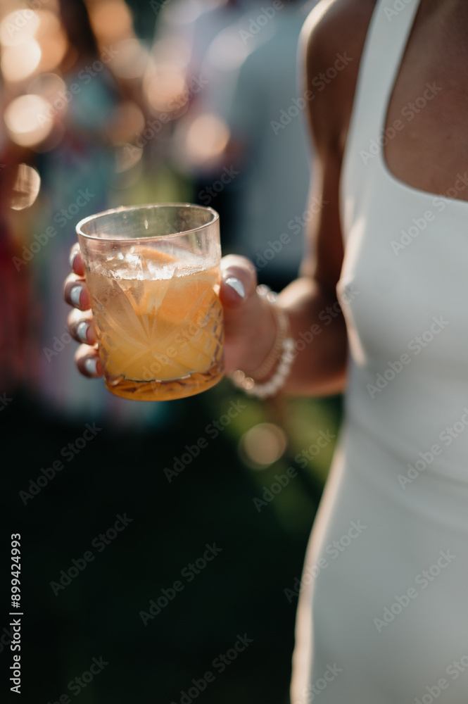Woman holding a cocktail in a crystal glass at a social event. Woman holding a cocktail in a crystal glass at a social event.