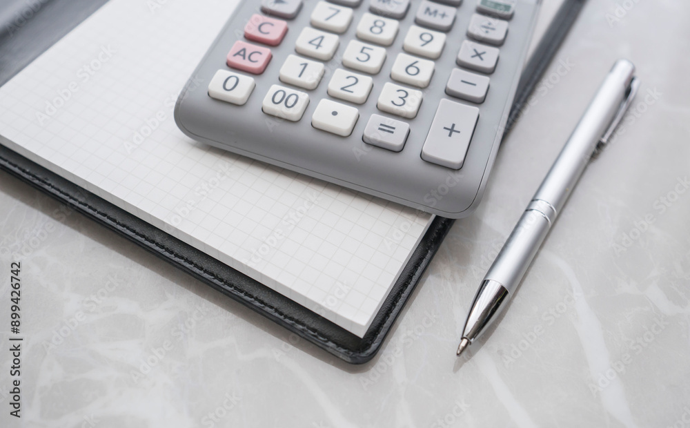calulator on the notepad and pen on the table calulator on the notepad and pen on the table
