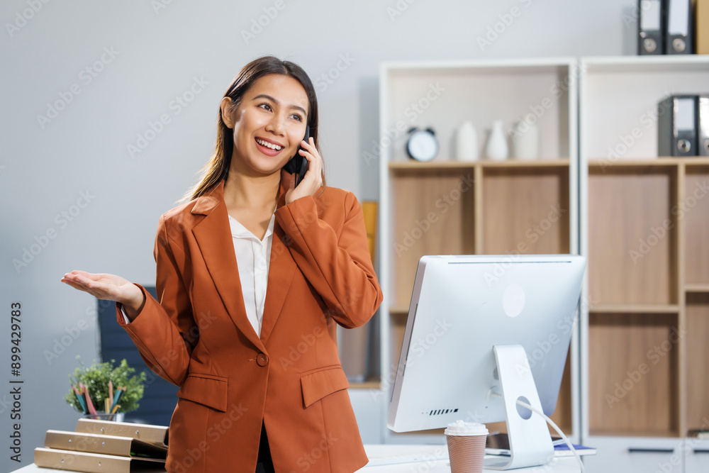 An Asian businesswoman sits at a table, working with a smile. She manages her online Kuya business with enthusiasm, showcasing her dedication and positive attitude while handling tasks efficiently. An Asian businesswoman sits at a table, working with a smile. She manages her online Kuya business with enthusiasm, showcasing her dedication and positive attitude while handling tasks efficiently.