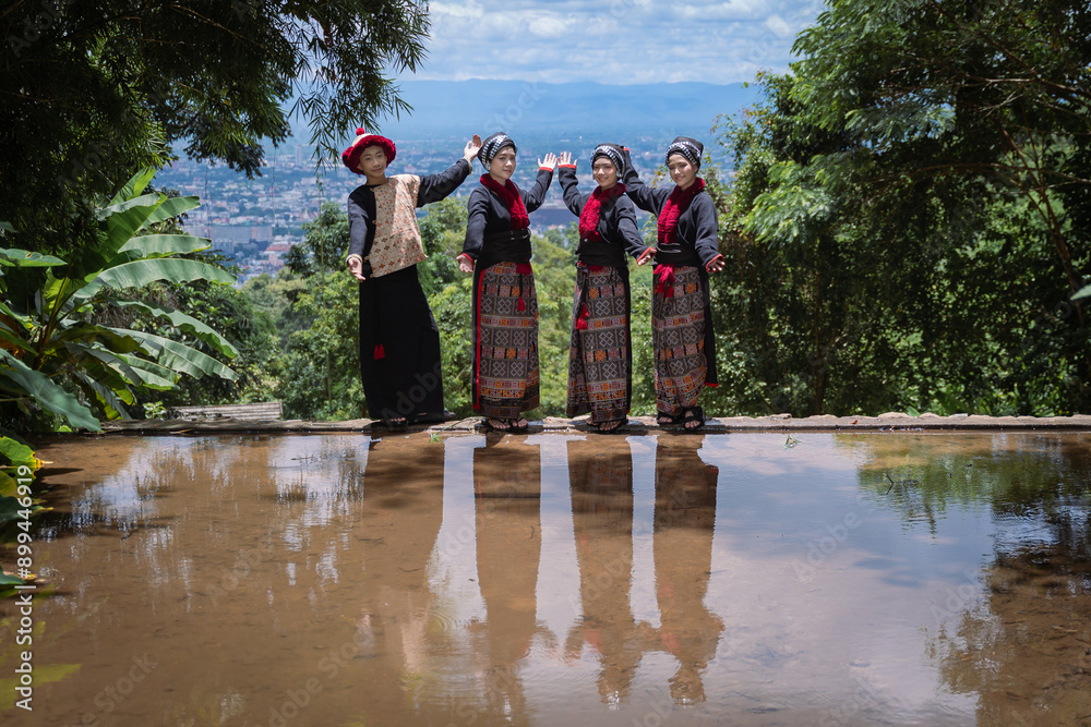 Obraz premium Younger cute Hmong or Yao Hill Tribes teenagers in beautiful traditional dress costumes with flowers in bamboo baskets travel to a natural waterfall in Chiang Mai, Thailand.