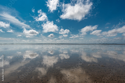 Ebbe am Wattenmeer an der deutschen Nordseeküste bei schönem Wetter und aufgelockerter Bewölkung, die sich im Waser spiegelt