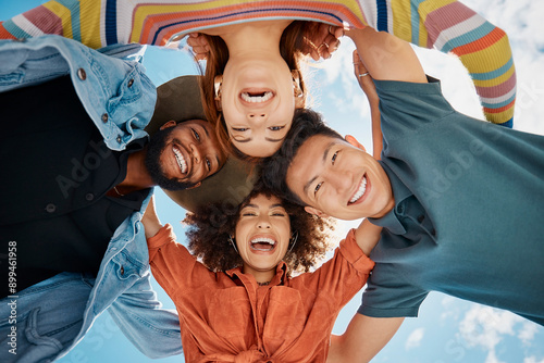 Friends, huddle and portrait in outdoor hug, solidarity and low angle for love on blue sky. People, social diversity and embrace for support or reunion, together and youth culture for motivation