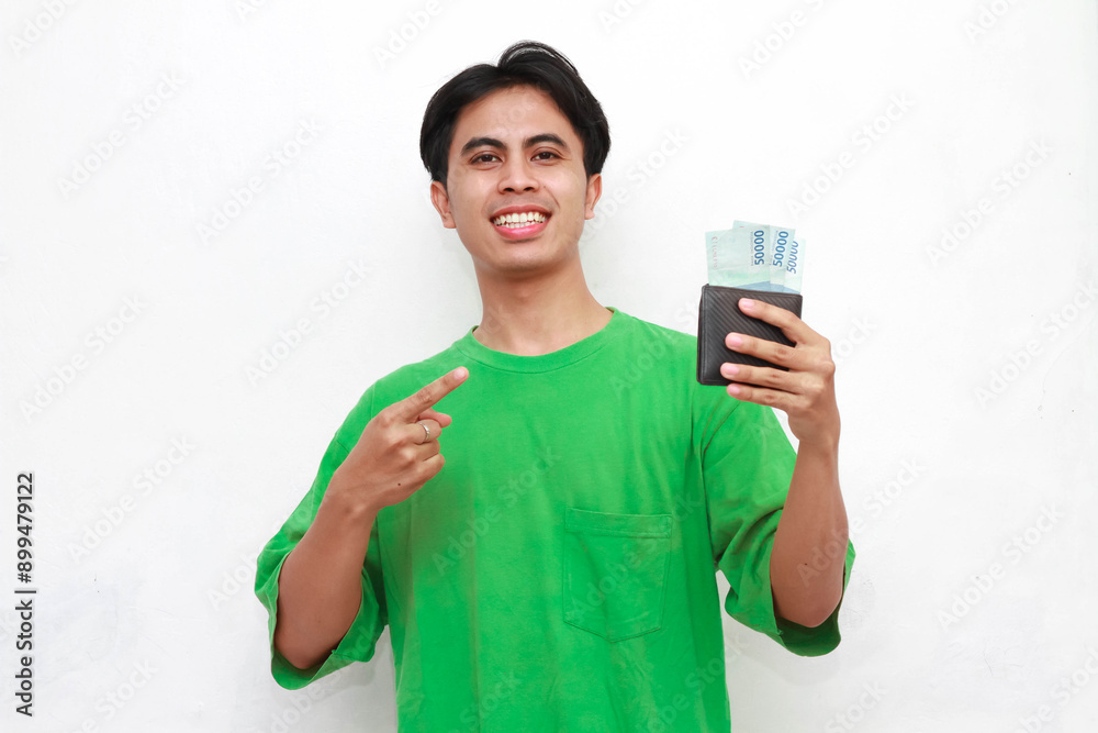Cheerful adult Asian man in green t-shirt posing holding wallet containing money isolated on white background Cheerful adult Asian man in green t-shirt posing holding wallet containing money isolated on white background