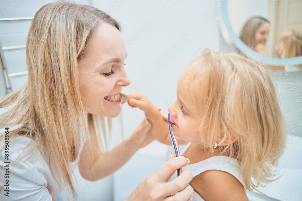 Woman and child brushing each other's teeth Woman and child brushing each other's teeth
