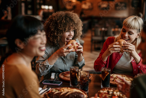 Young happy people having lunch together. Focus on a smiling female talking and grabbing a chips
