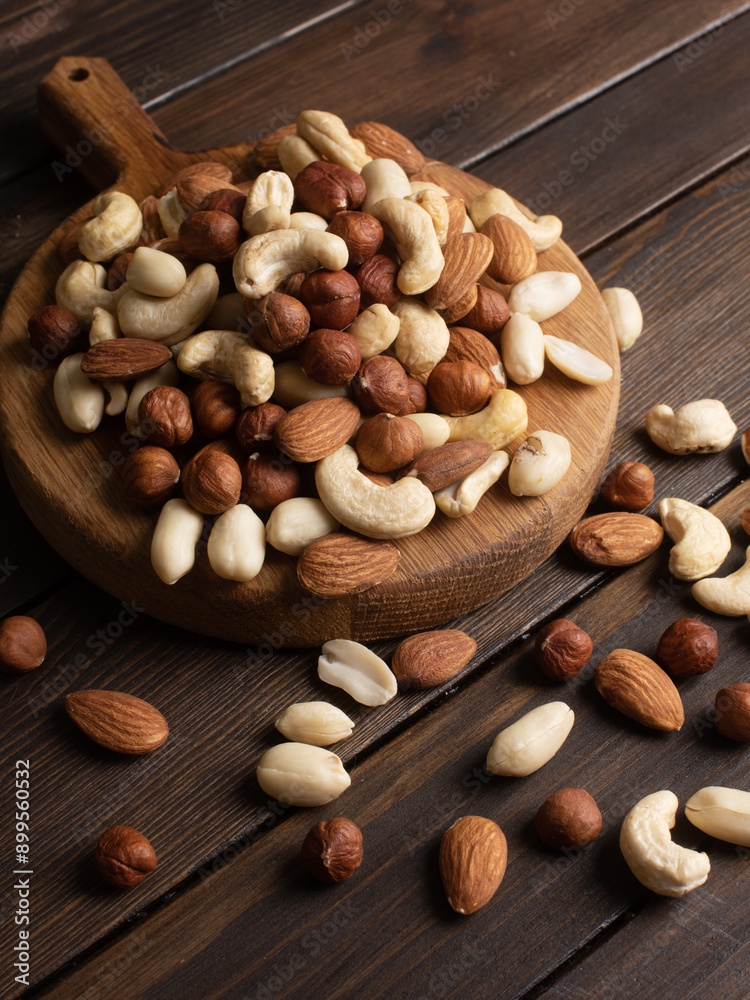 mix of nuts from almonds, walnuts, cashews, peanuts on a wooden plate close up view mix of nuts from almonds, walnuts, cashews, peanuts on a wooden plate close up view